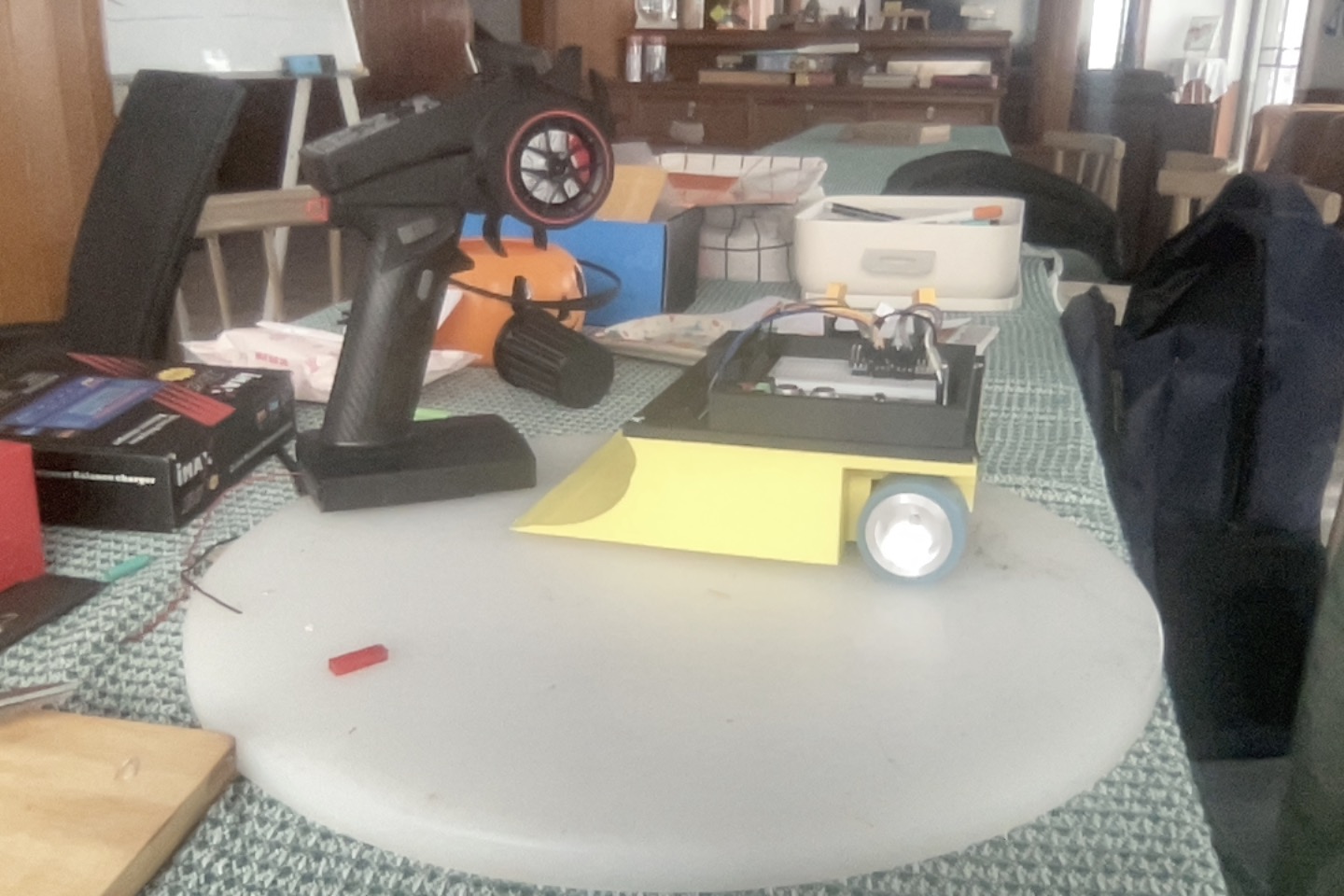 The assembled yellow and black Version 2 sumo robot beside its transmitter